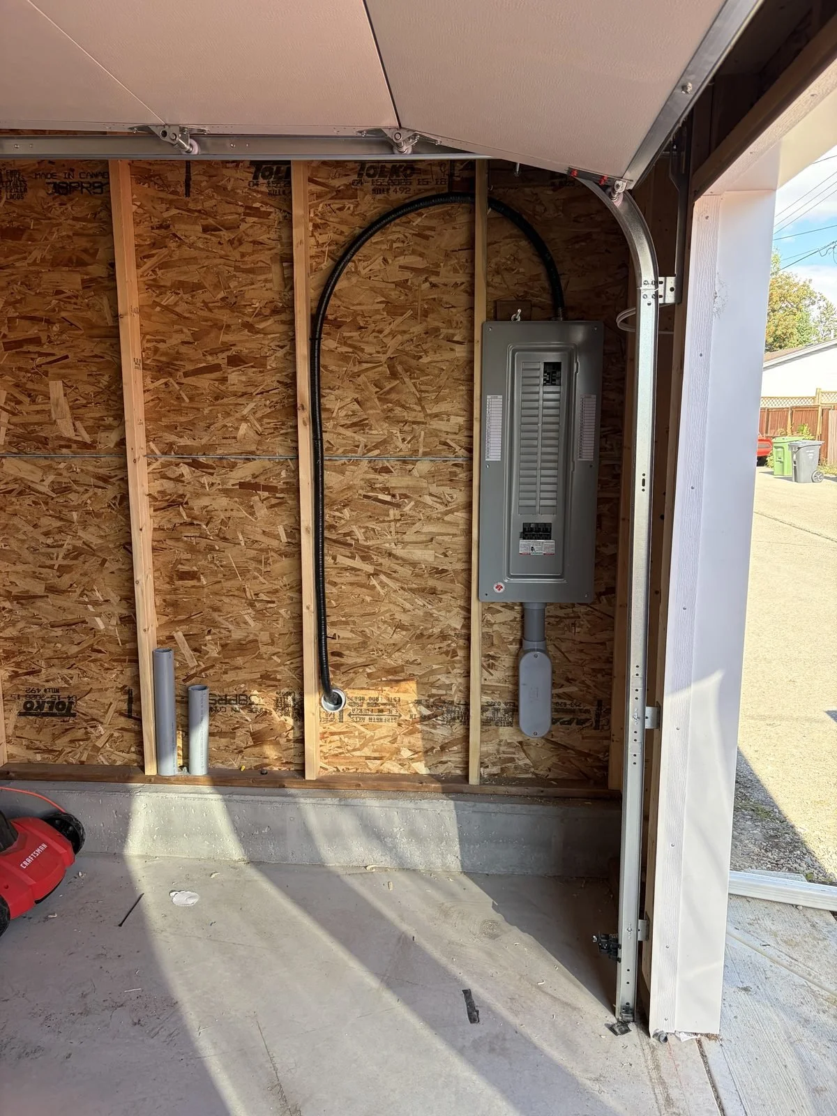 New 200 amp electrical panel and conduit on the garage wall after a service upgrade by Koop Electrical in Dover, Calgary