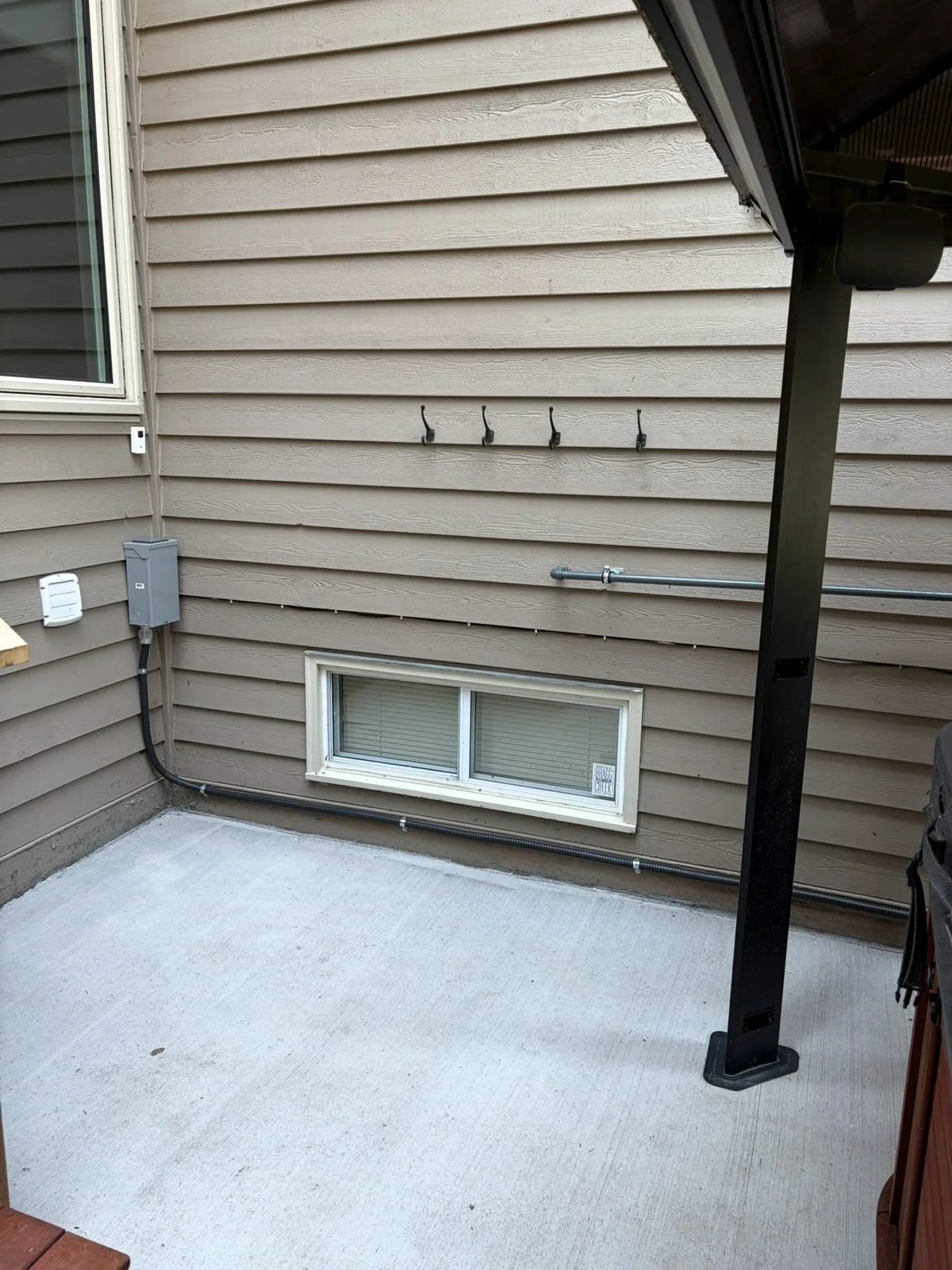 GFCI spa disconnect mounted on the exterior wall within sight of the hot tub, with conduit running along the house, Redwood Meadows