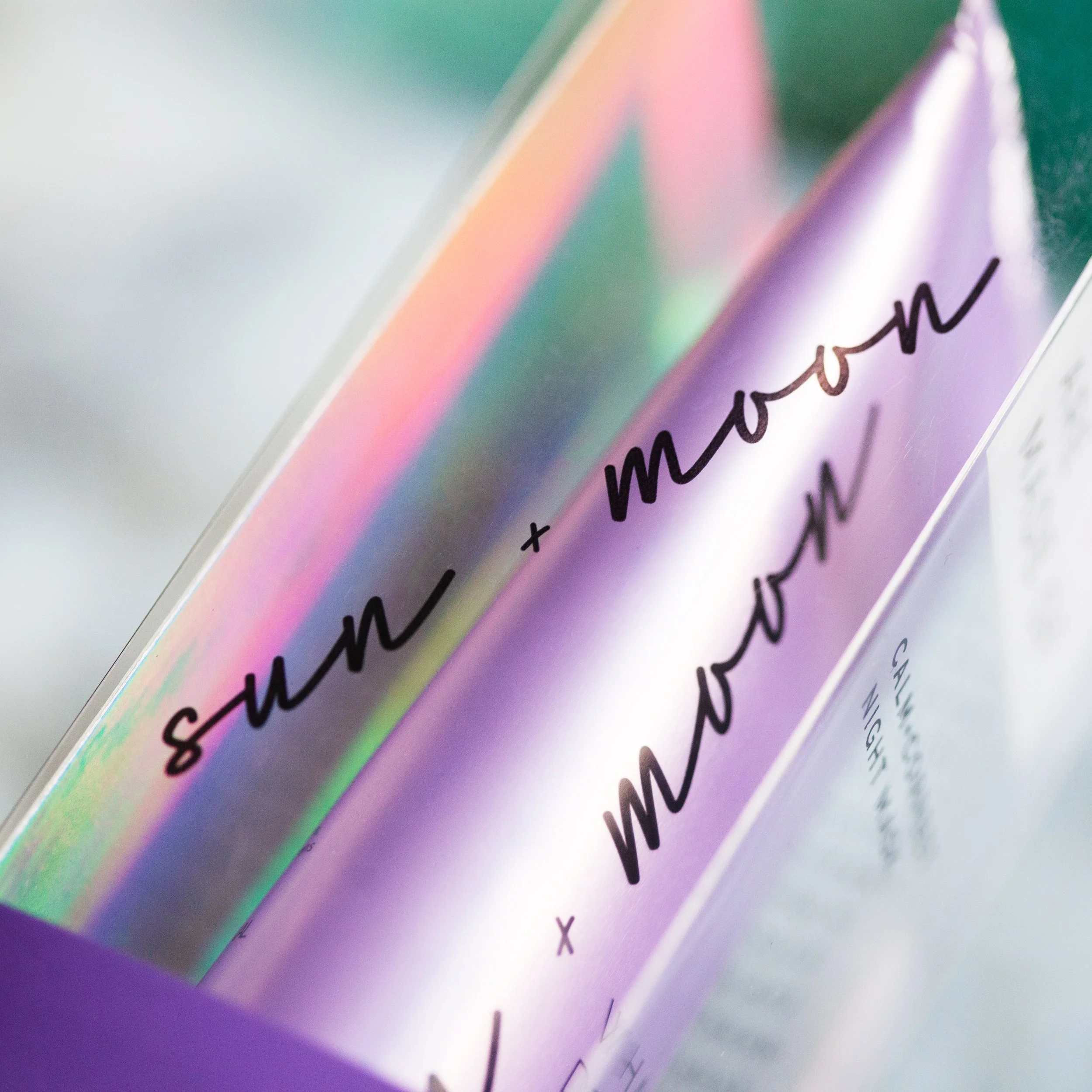 Close-up of holographic gift wrapping paper with black cursive writing.