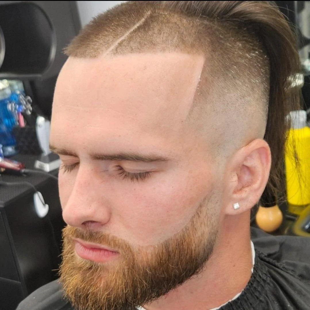 Front view of a men's top knot with a hard part, high skin fade, and full beard, cut by Ben Santiago at Gem City Barbers in Erie, PA.