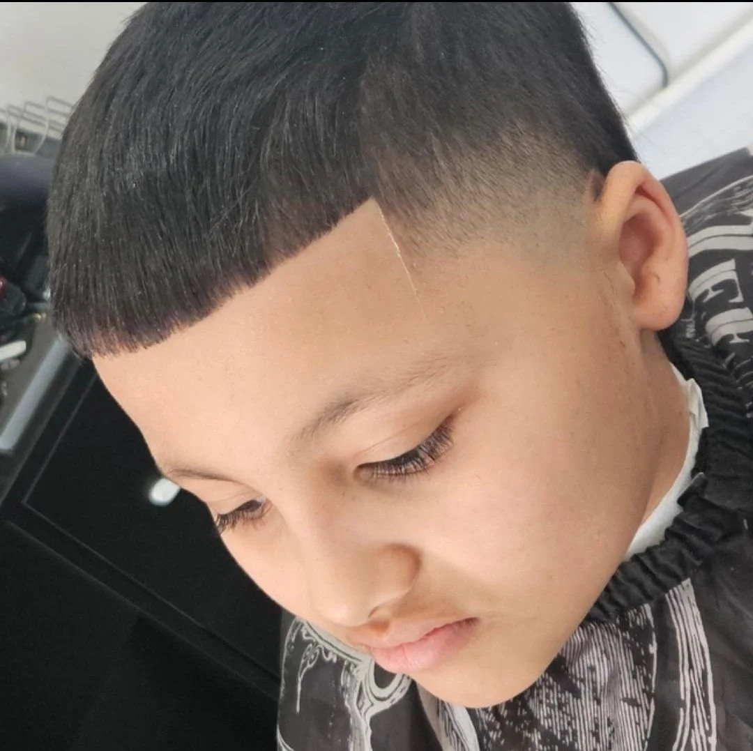 Front and side view of a kid's Edgar-style haircut with a straight fringe and clean skin fade, done at Gem City Barbers in Erie, PA.