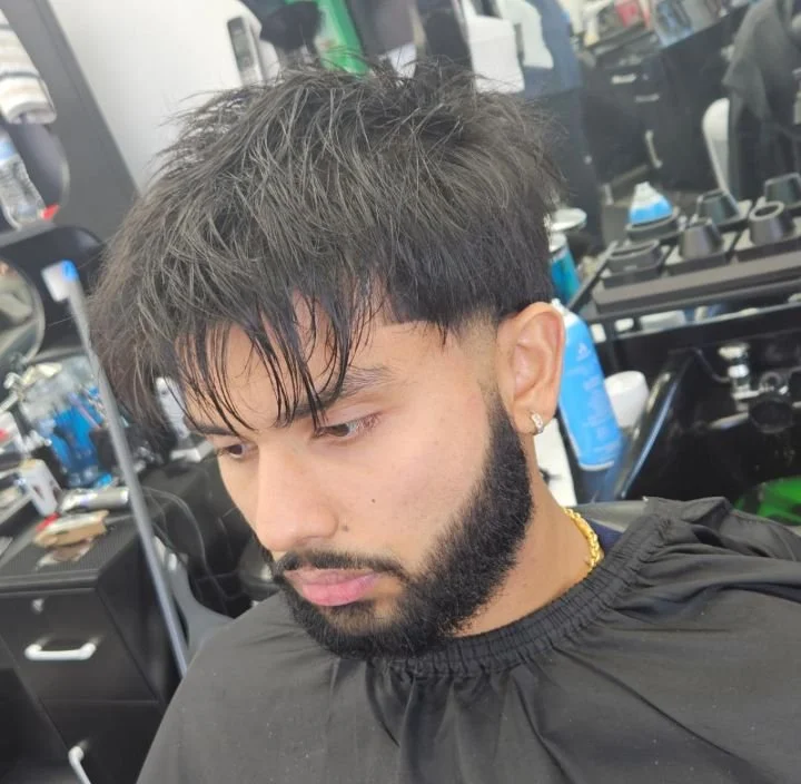 Front view of a men's long textured fringe with a layered finish and full beard, cut by Ben Santiago at Gem City Barbers in Erie, PA.