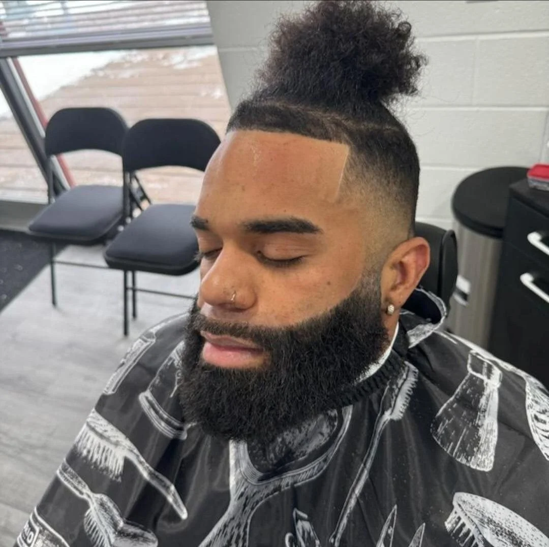 Front view of a men's high top man bun hairstyle with a sharp line-up, mid fade, and full shaped beard, done at Gem City Barbers in Erie, PA.