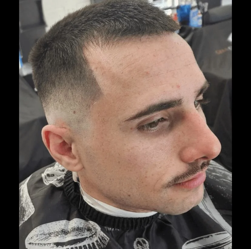 Front view of a men's short buzz cut with a high skin fade and clean line-up, cut by Ben Santiago at Gem City Barbers in Erie, PA.