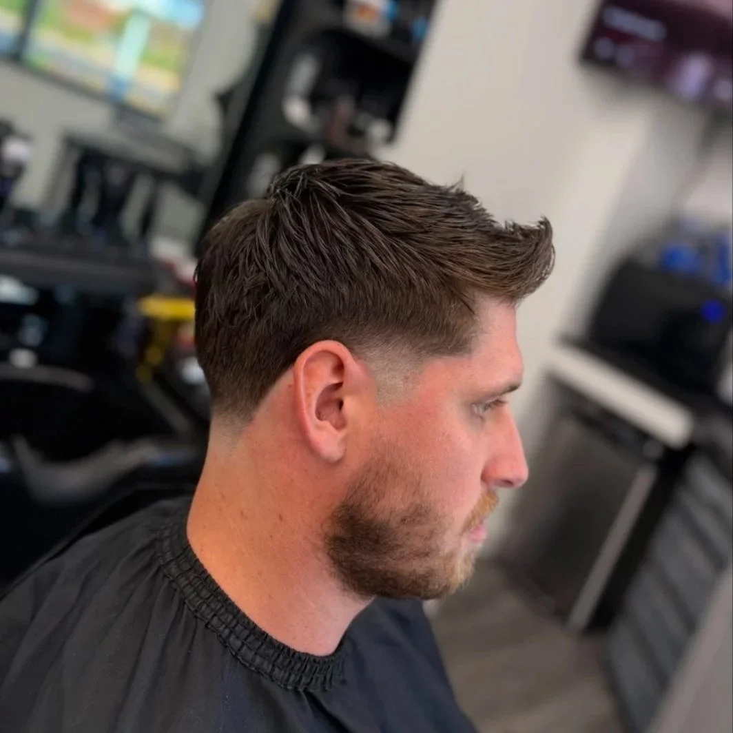 Side profile of a men's textured crop haircut with a low taper fade and a short groomed beard, styled at Gem City Barbers in Erie, PA.