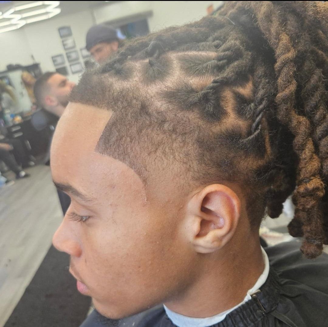Side profile of men's loc retwist with a sharp line-up and taper fade, styled by Ben Santiago at Gem City Barbers in Erie, PA.