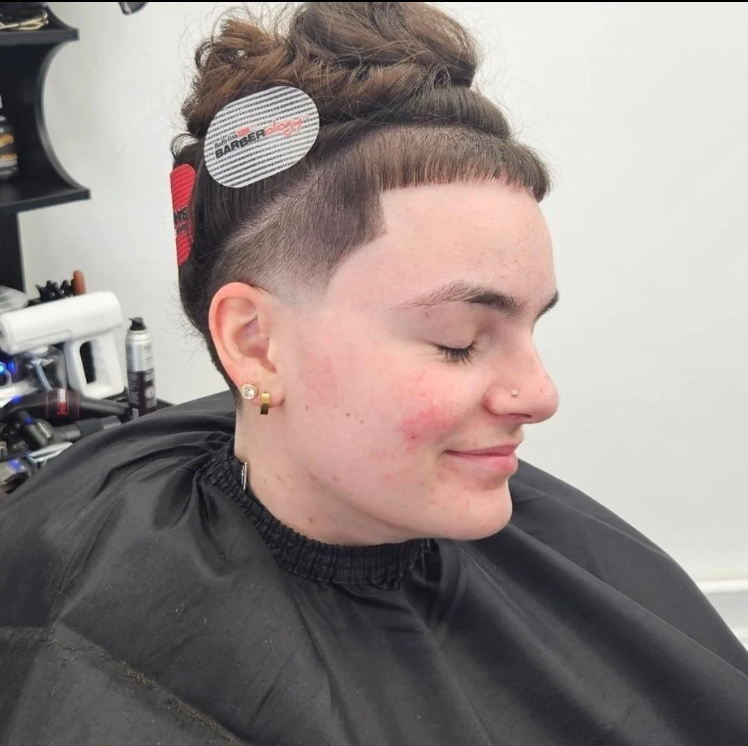 Side profile of an undercut hairstyle with shaved sides and longer hair clipped up on top, styled at Gem City Barbers in Erie, PA.