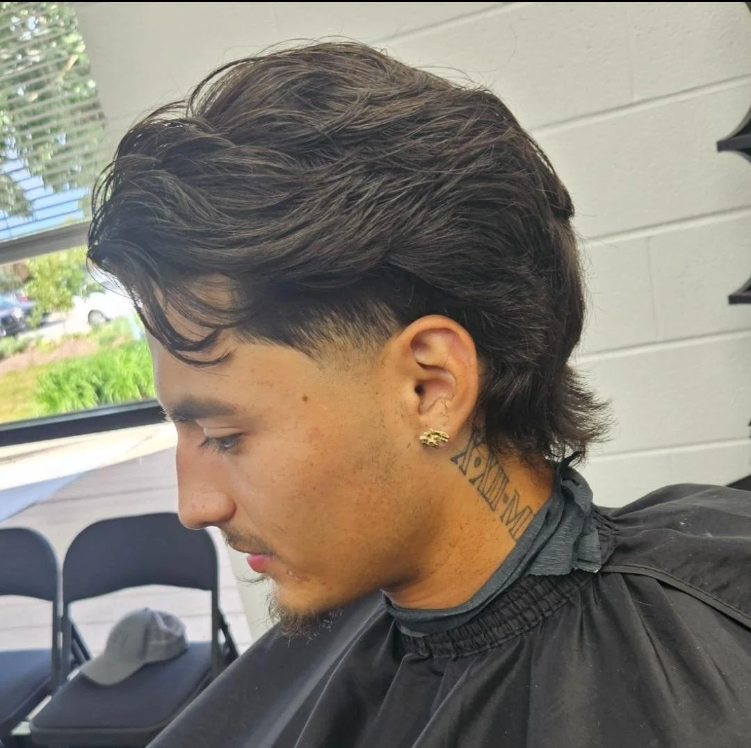 Side profile of a men's modern mullet with textured waves on top, a mid fade, and longer length in the back, done at Gem City Barbers in Erie, PA.