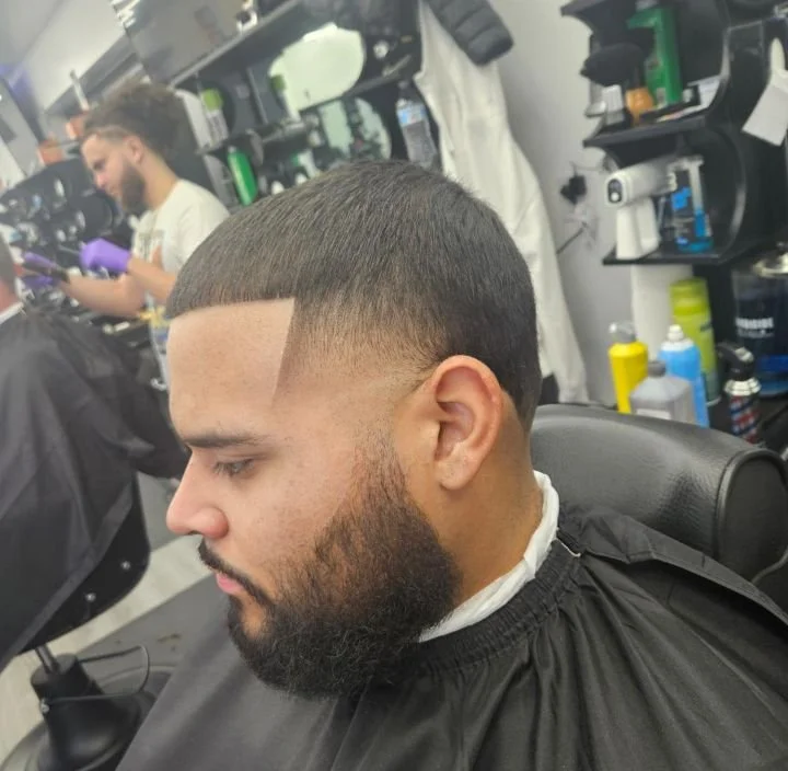 Side view of a men's short crop fade with a sharp line-up and shaped beard, cut by Ben Santiago at Gem City Barbers in Erie, PA.