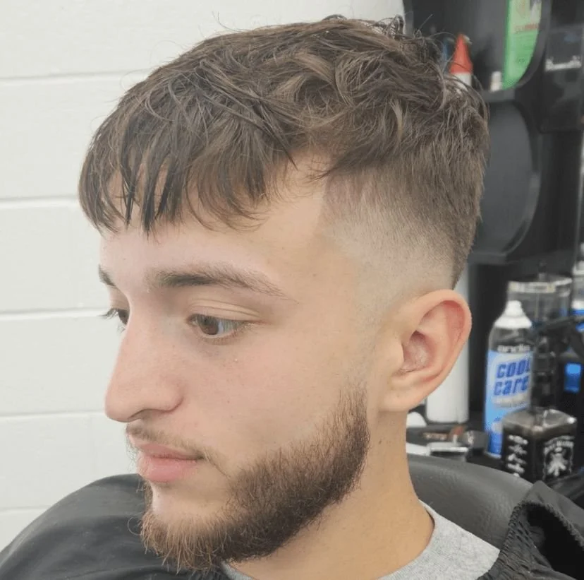 Front view of a men's textured fringe with a low fade and short beard, cut by Ben Santiago at Gem City Barbers in Erie, PA.