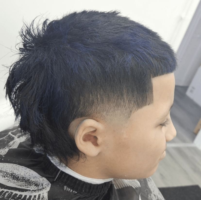Side view of a kid's textured mullet with a mid fade and longer layers in the back, cut by Ben Santiago at Gem City Barbers in Erie, PA.