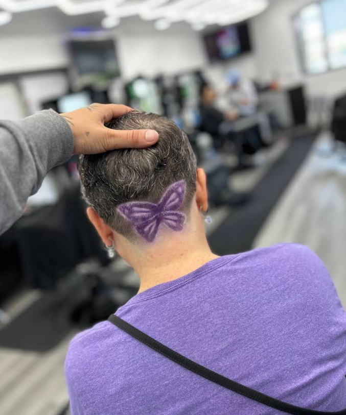 Back view of a custom hair design featuring a purple butterfly shaved and colored into the nape, created by a barber at Gem City Barbers in Erie, PA.