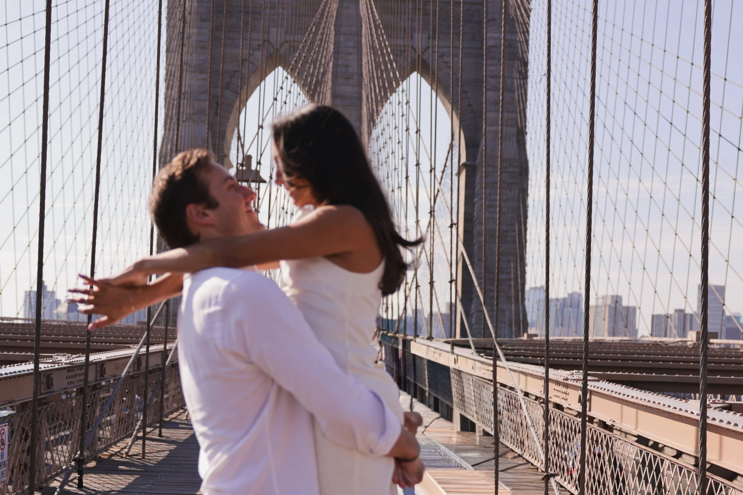 A couple embracing and about to kiss on the Brooklyn Bridge in New York City during daytime.