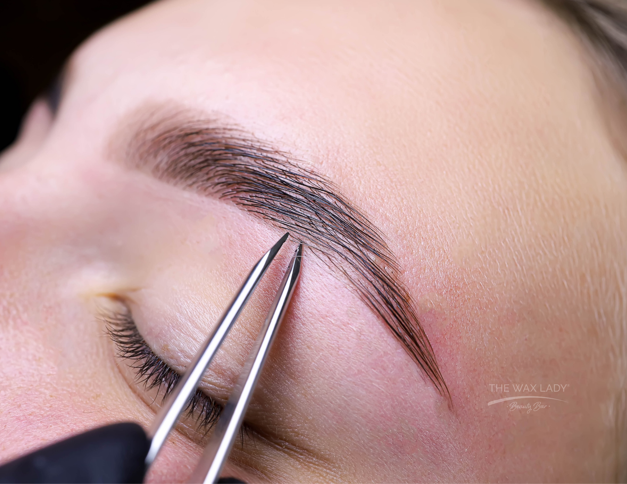 Close-up of a person's brows getting tweezed and shaped