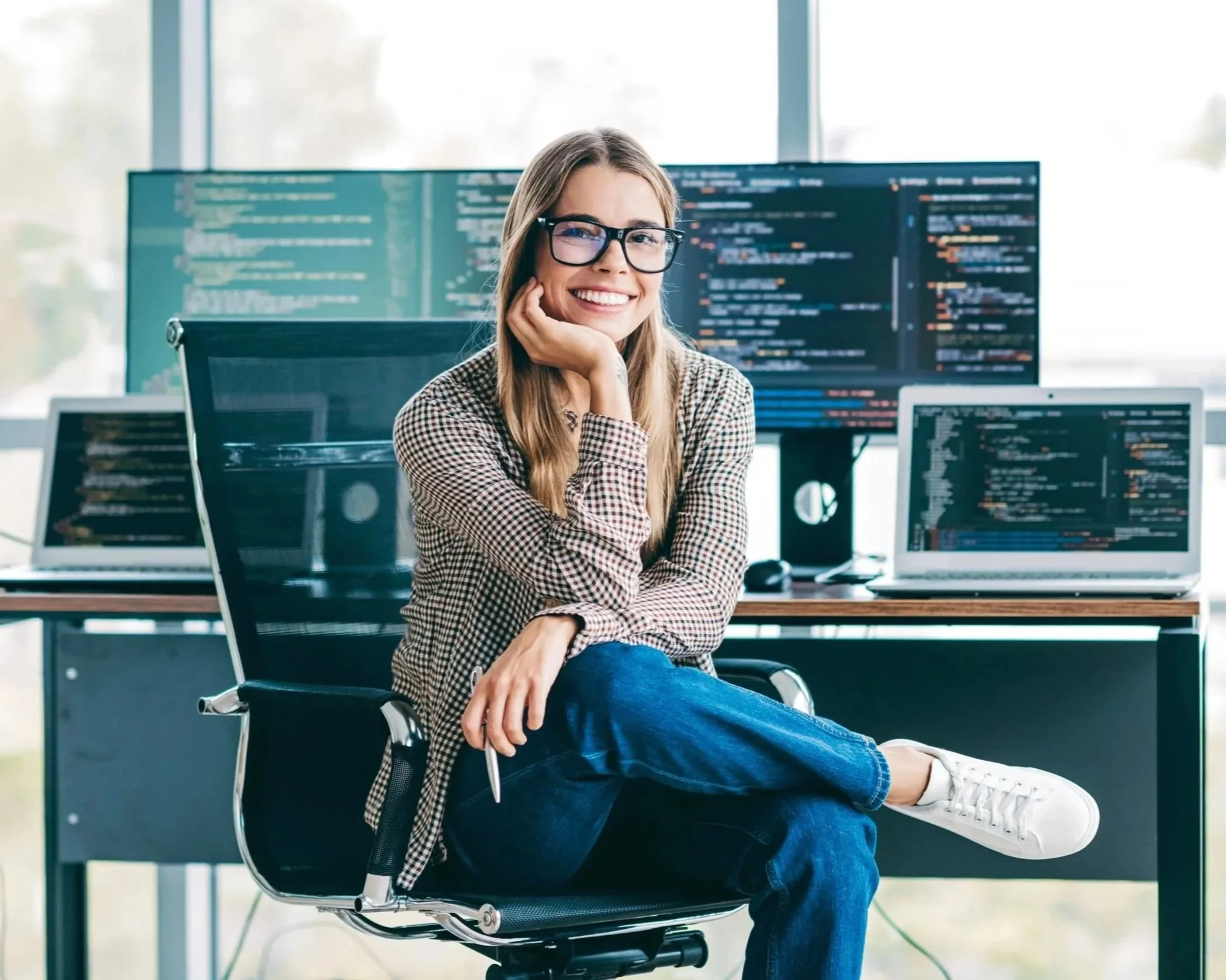 Smiling professional looks up from a laptop in a bright home office