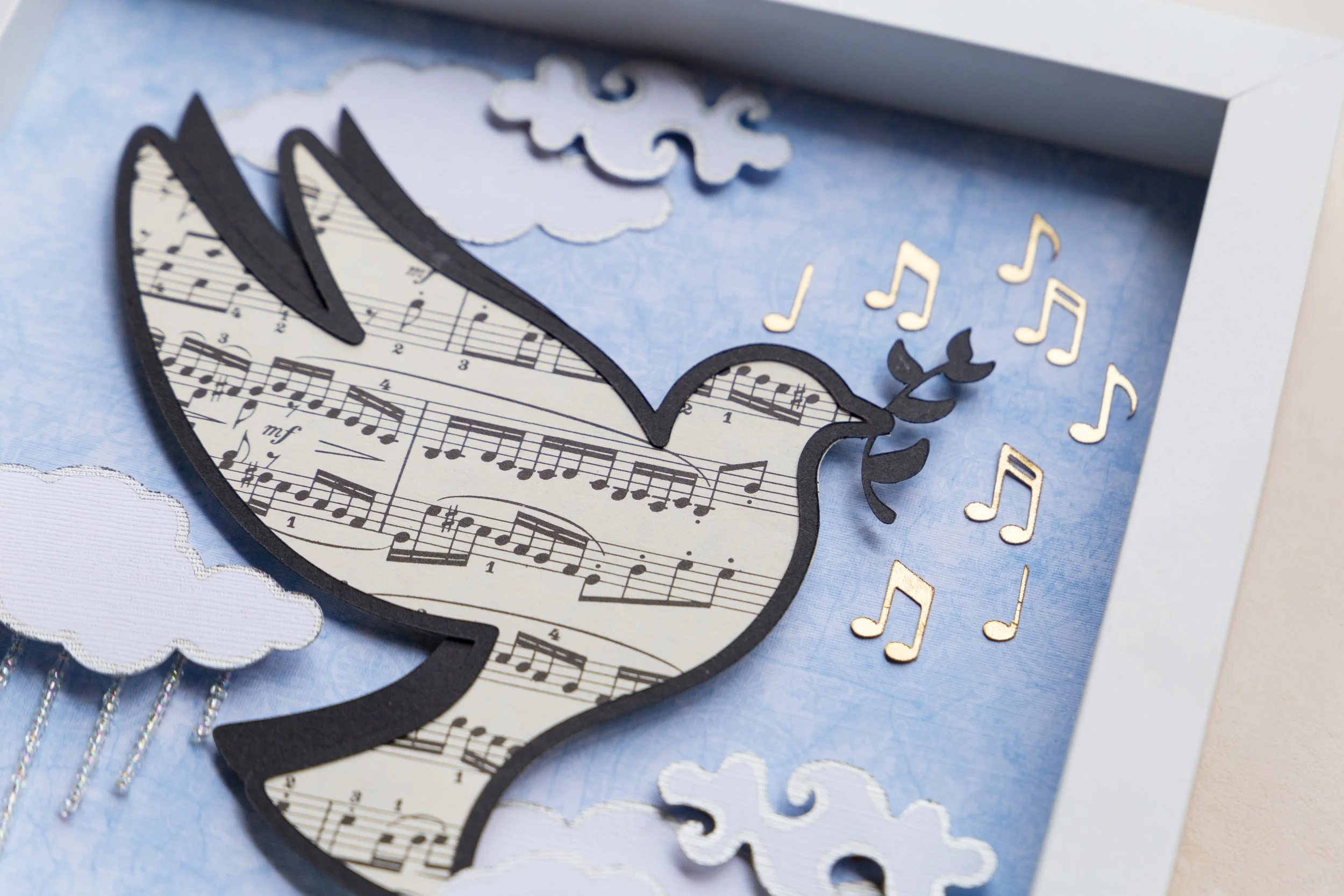 A handmade greeting card with musical notes, cloud cutouts, and a guitar-shaped cutout featuring musical sheet music.
