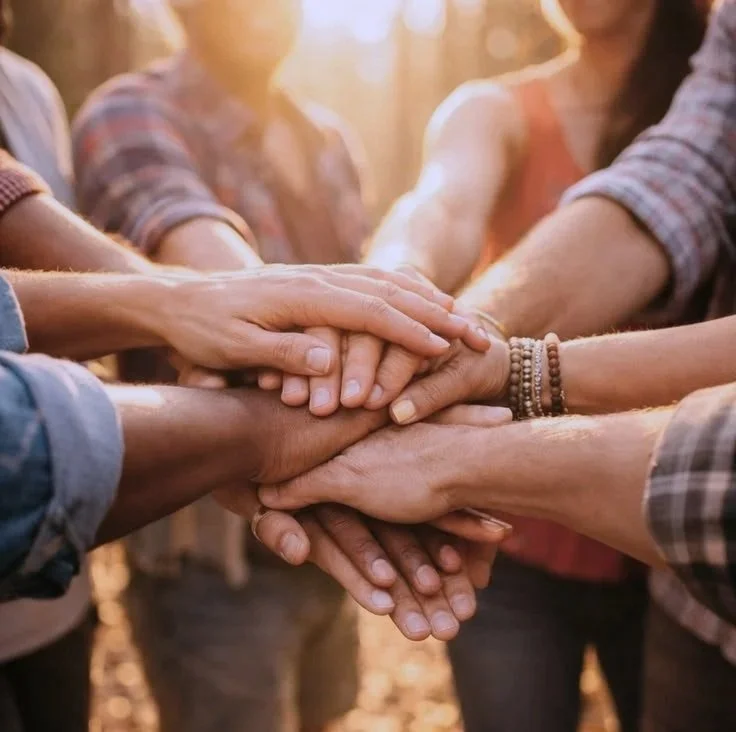 Multiple people stacking their hands together in a show of unity and teamwork.