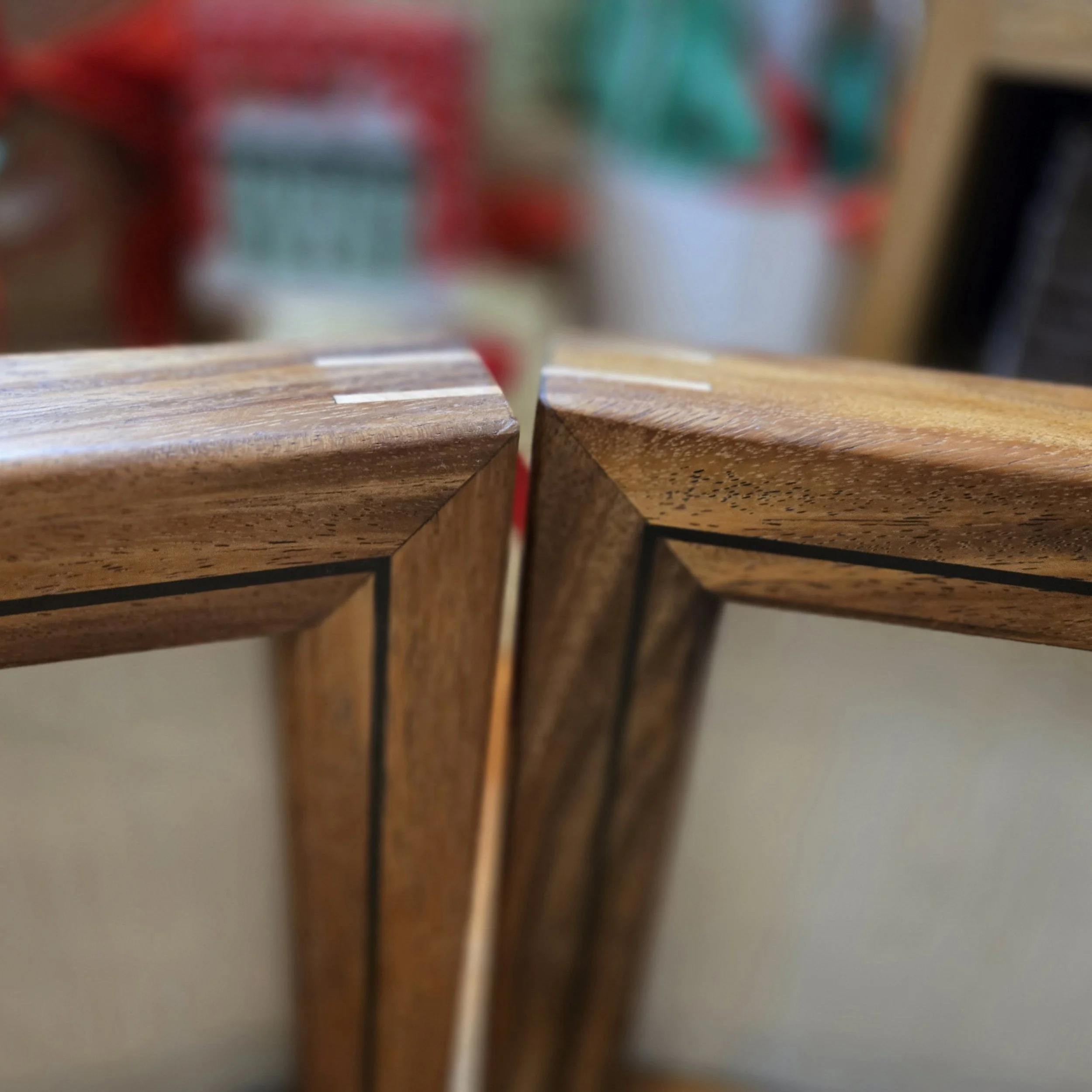 Close-up of the corner joint of wooden furniture with a dark line inlay in the wood grain.