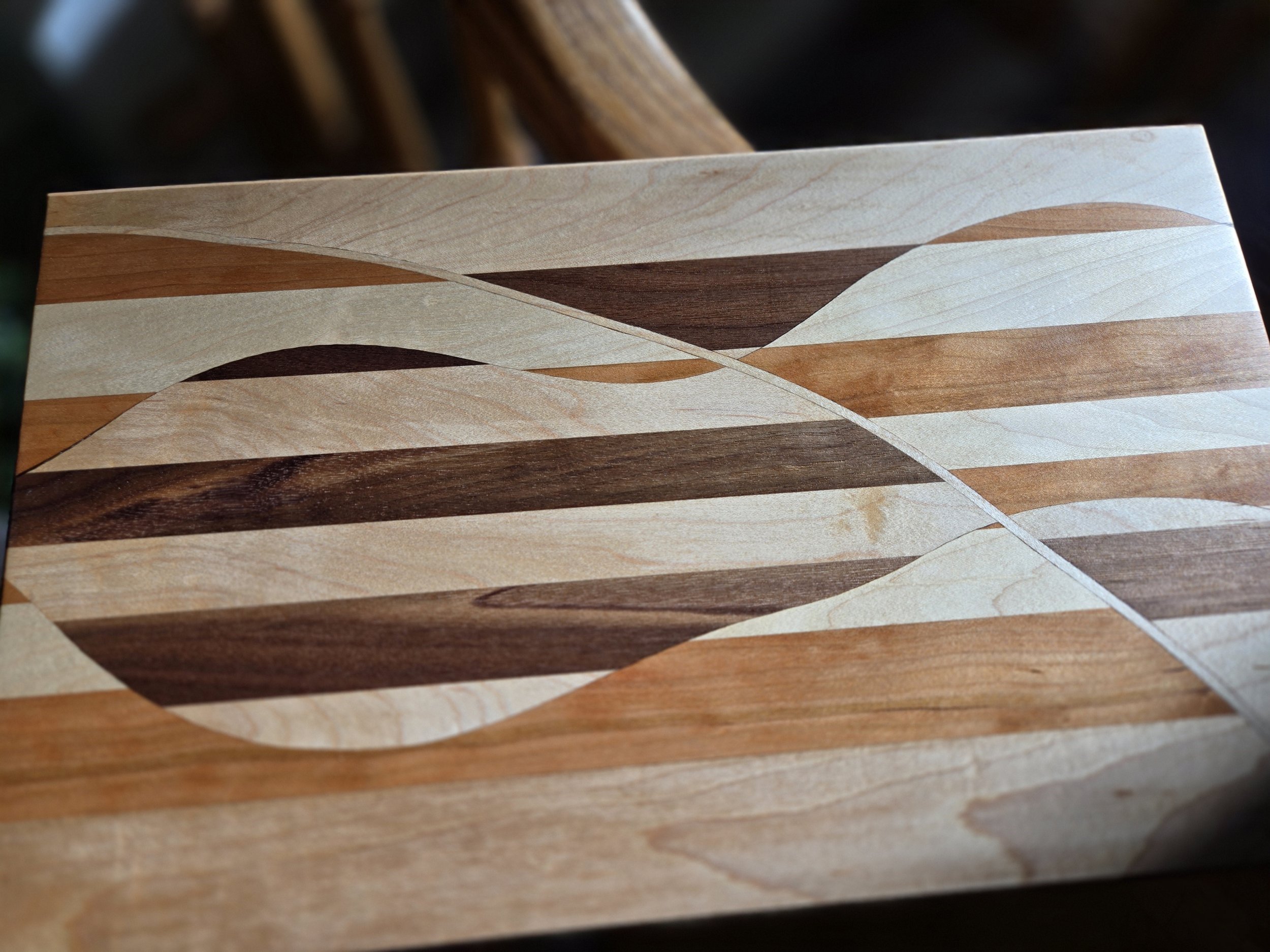 Close-up of a wooden surface with a decorative pattern made from multiple types of wood in various colors and shades, creating an abstract design.