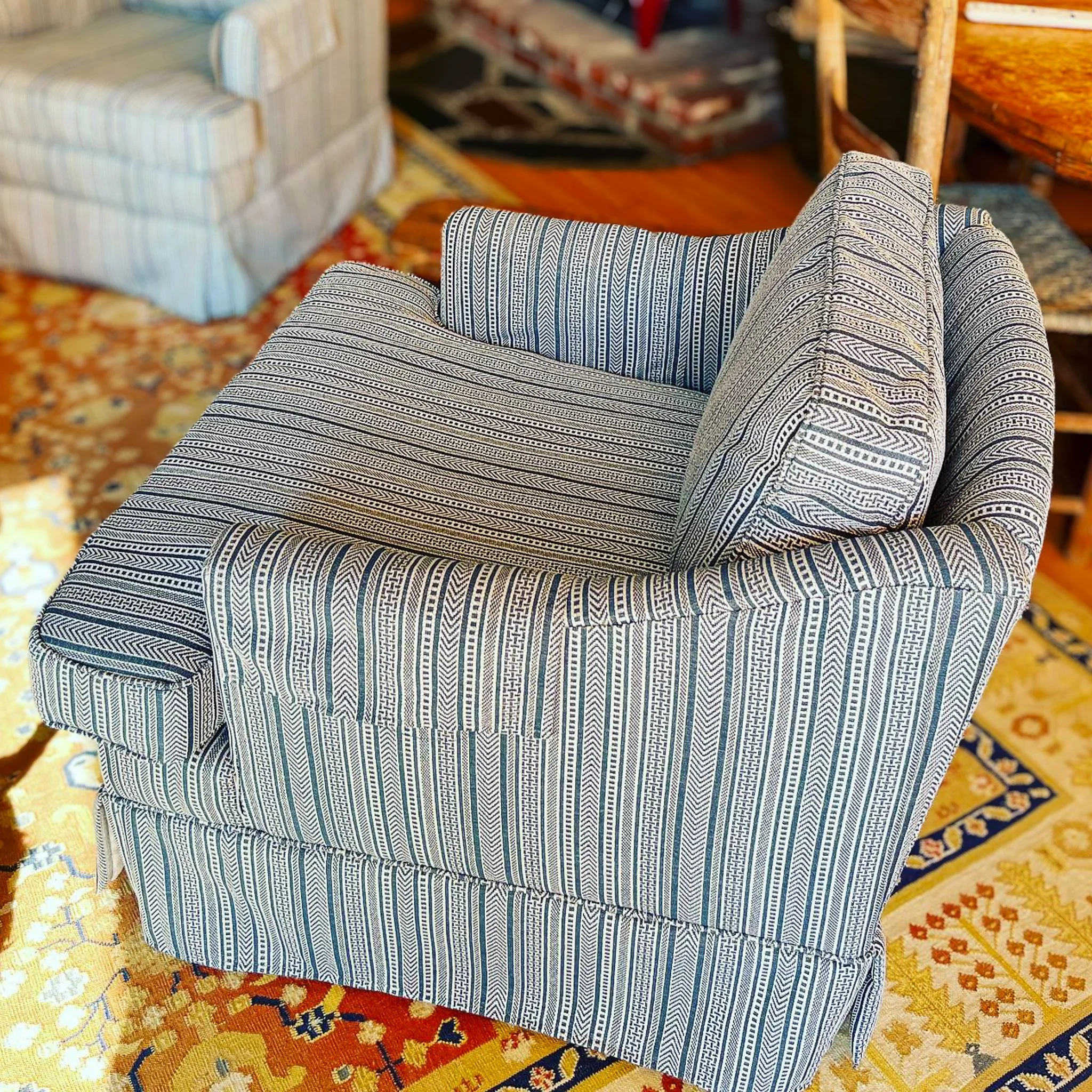 A patterned armchair with striped upholstery positioned on a decorative rug in a living room.
