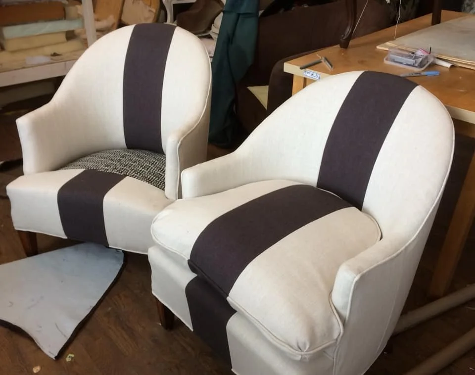 Two upholstered armchairs with black and white fabric, placed in a workshop or storage area.