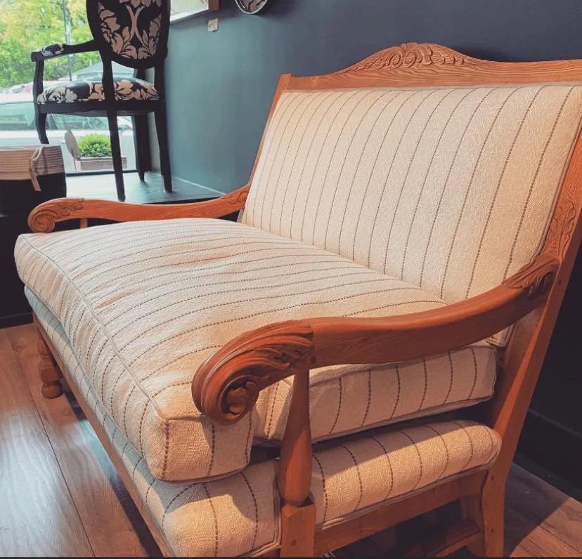 A vintage wooden sofa with beige striped upholstery in the atelier.