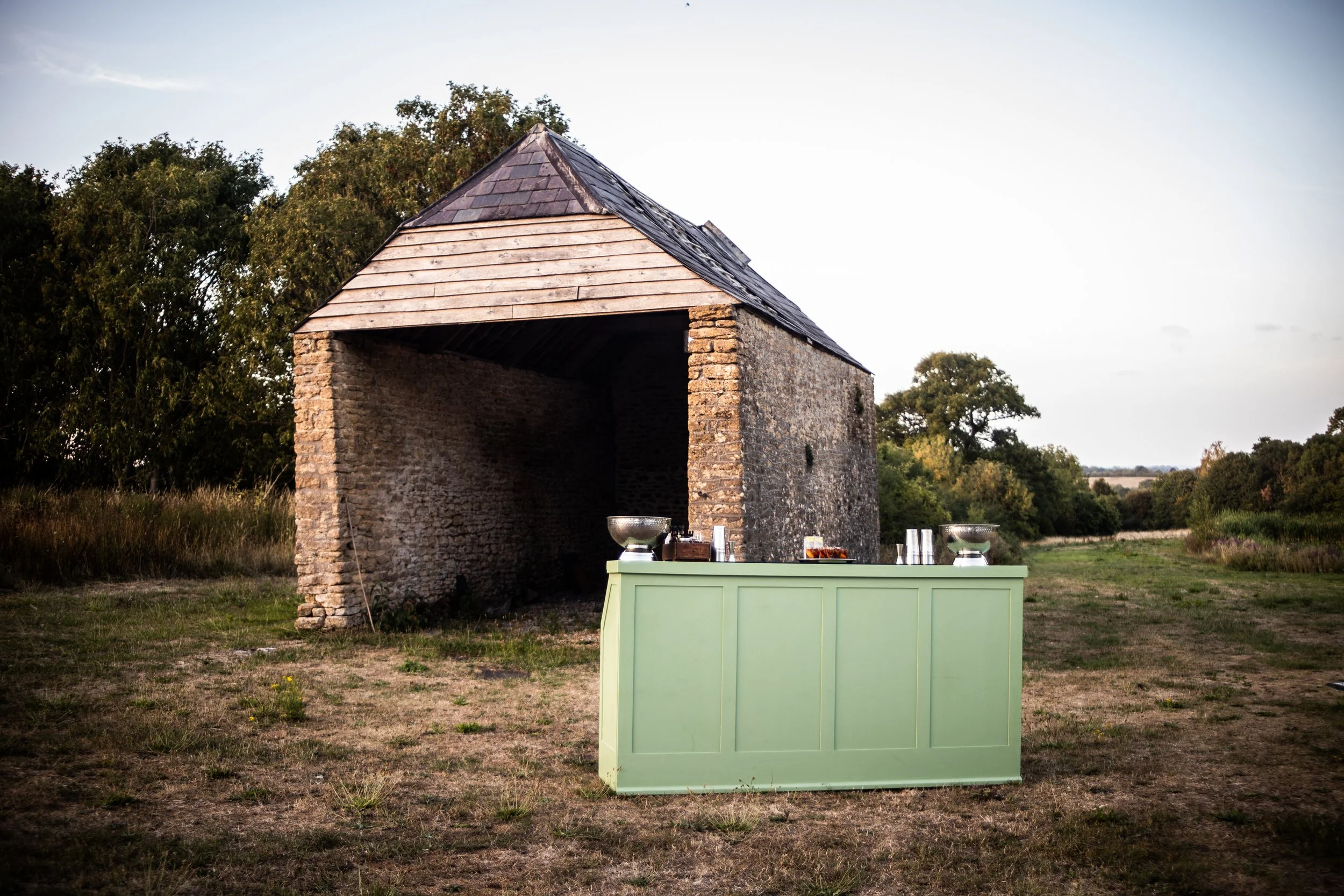 A portable cocktail bar station in front of a rustic farmyard barn