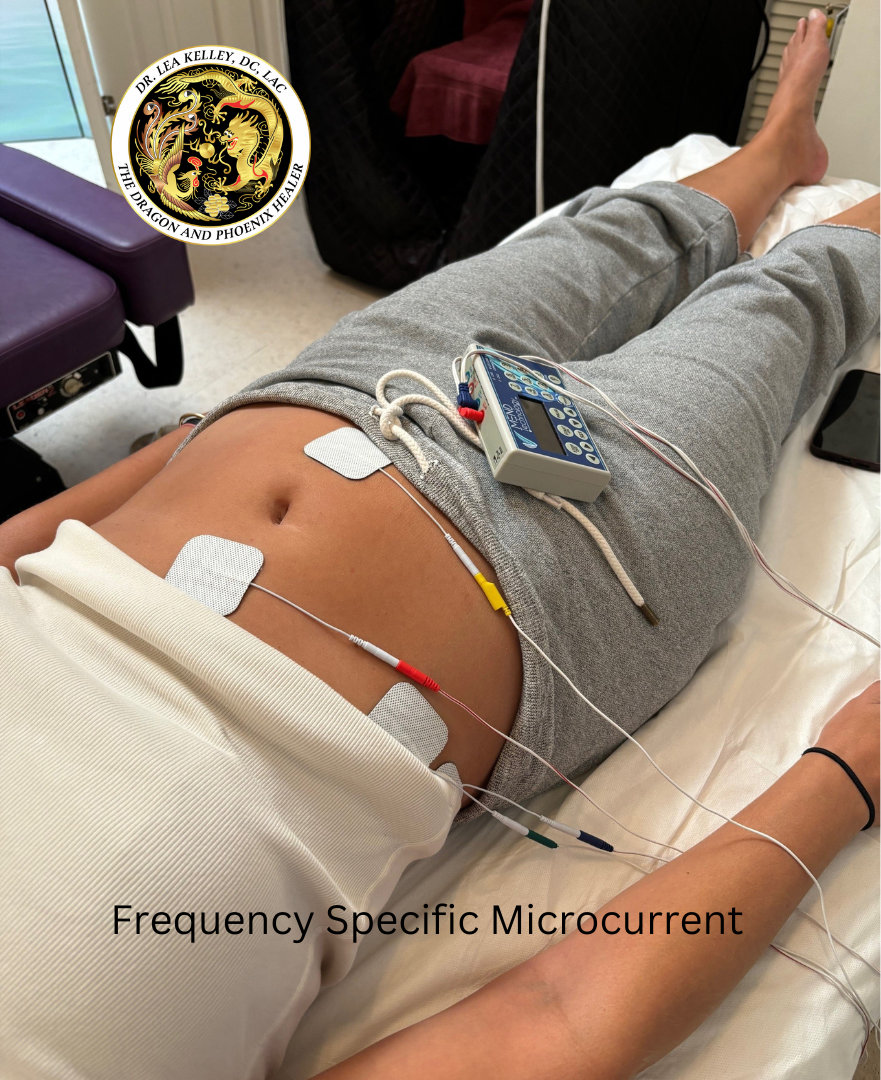 A pic of a woman on her back with EMS pads on her abdomen receiving a FSM therapy.