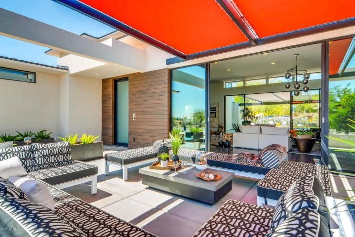 Modern luxury Scottsdale outdoor patio with black and white patterned seating, succulents, and floor to ceiling sliding glass doors opening to the living space.