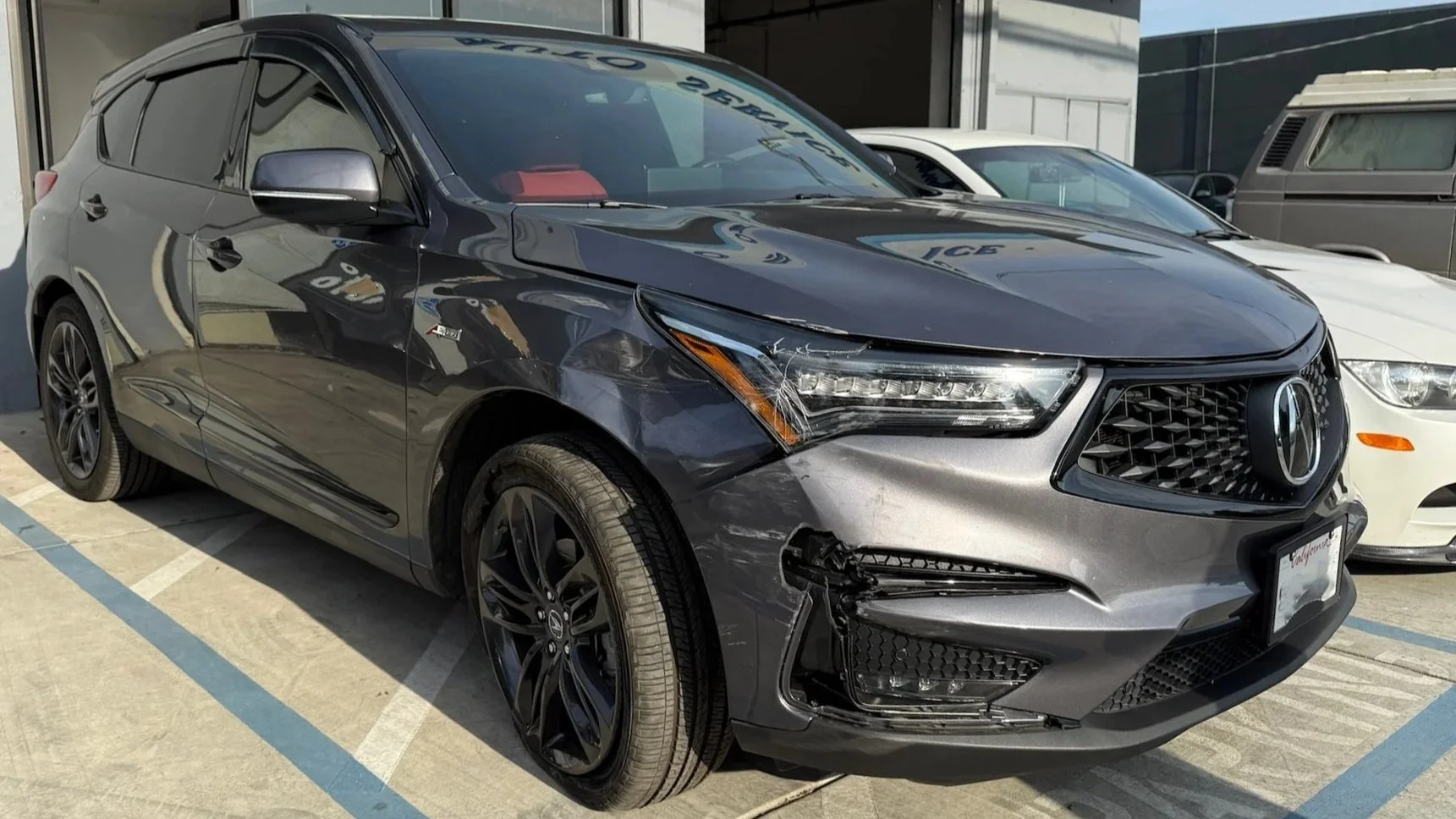 Black Acura SUV with front-end damage parked in a lot.