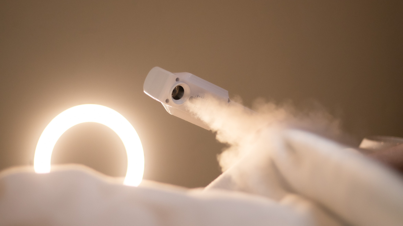 Client receiving a facial treatment with steam and ring light
