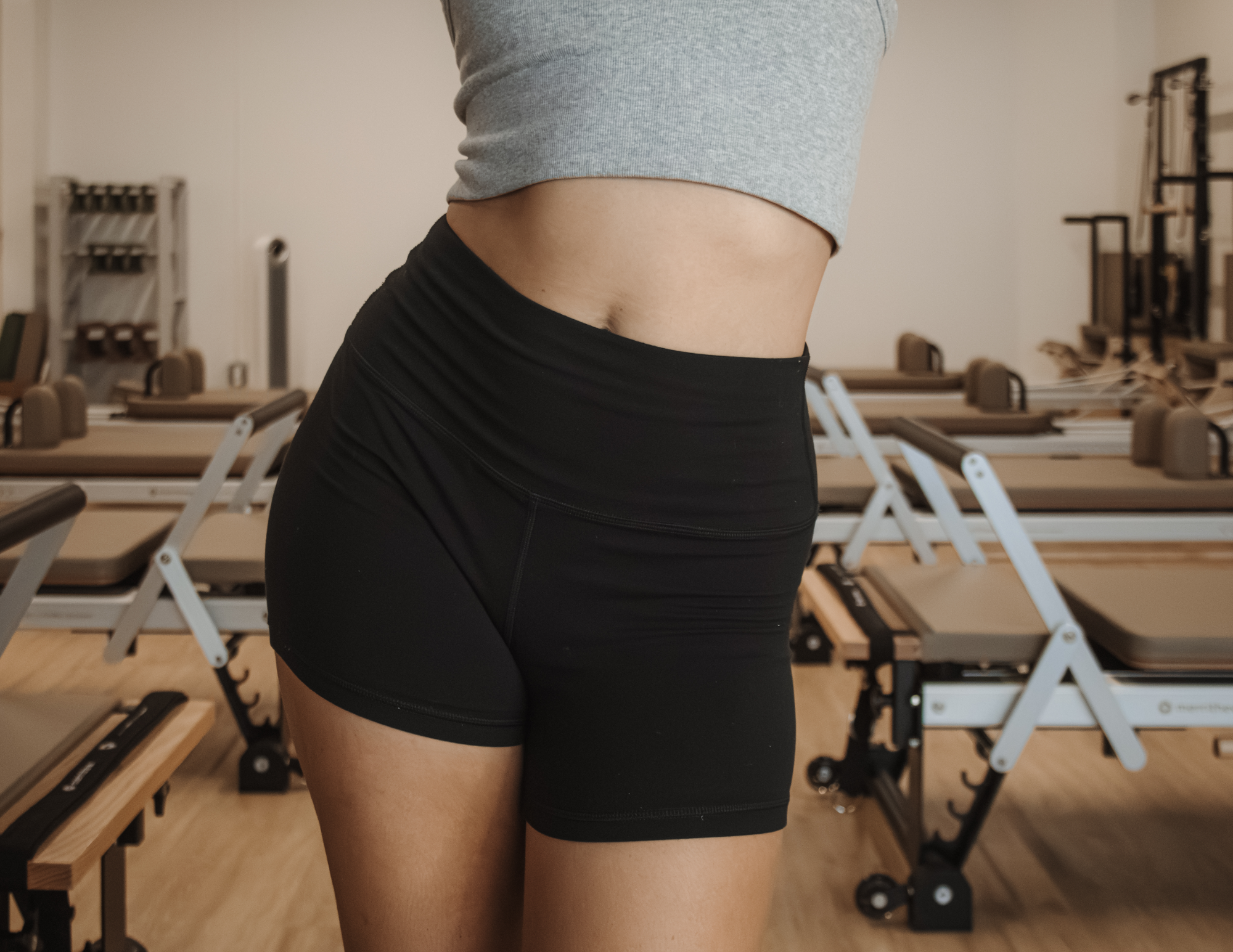 Person standing in a Pilates studio with reformers in the background