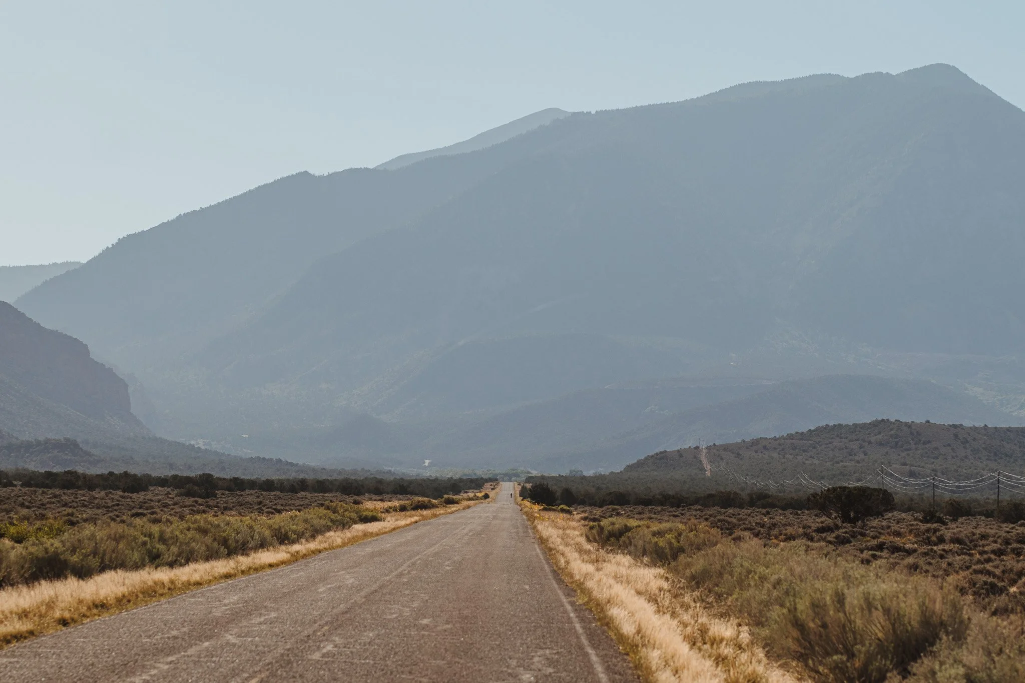 Long desert road leading toward distant mountains beneath a clear sky.