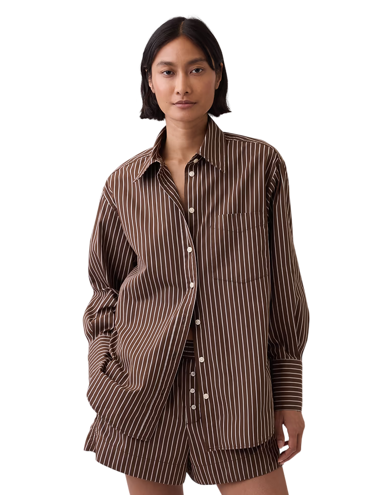 Woman in brown and white striped pajama set, standing against a plain background.