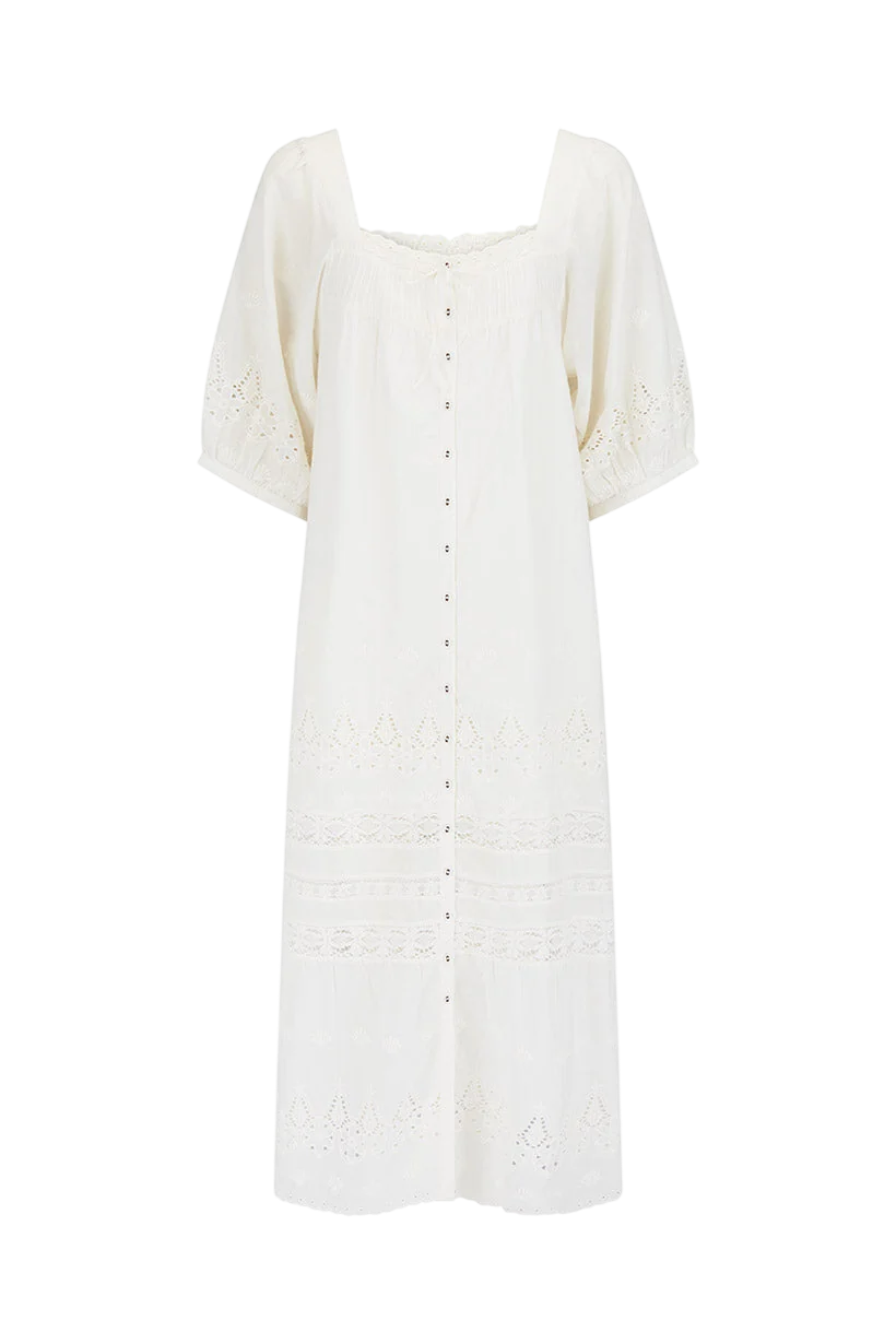 A long white dress with embroidery and button details.