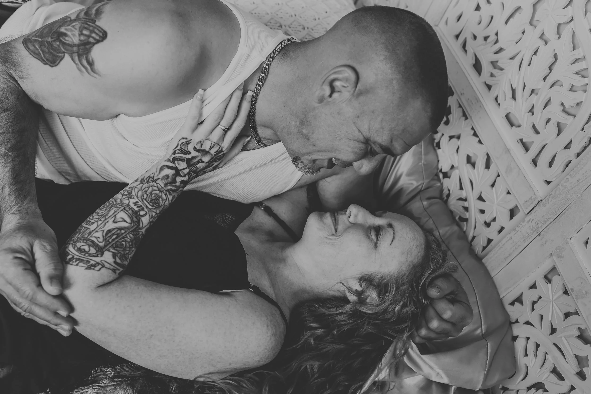 Man and woman laying in bed looking at each other lovingly