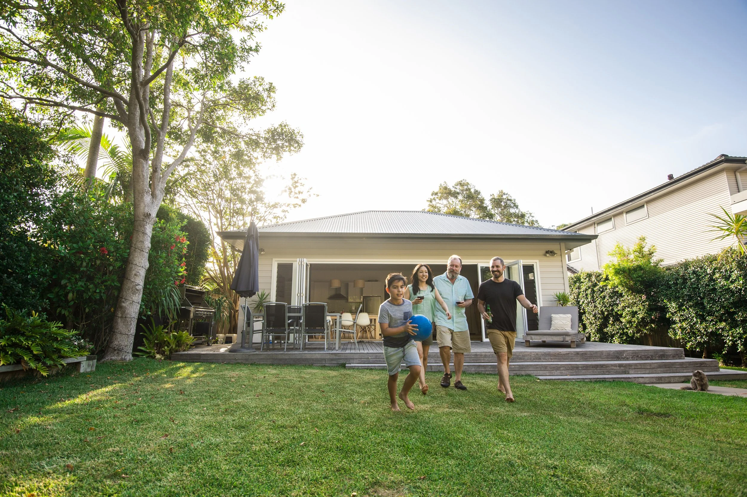 A family walking across the lawn towards their home on a sunny afternoon.
