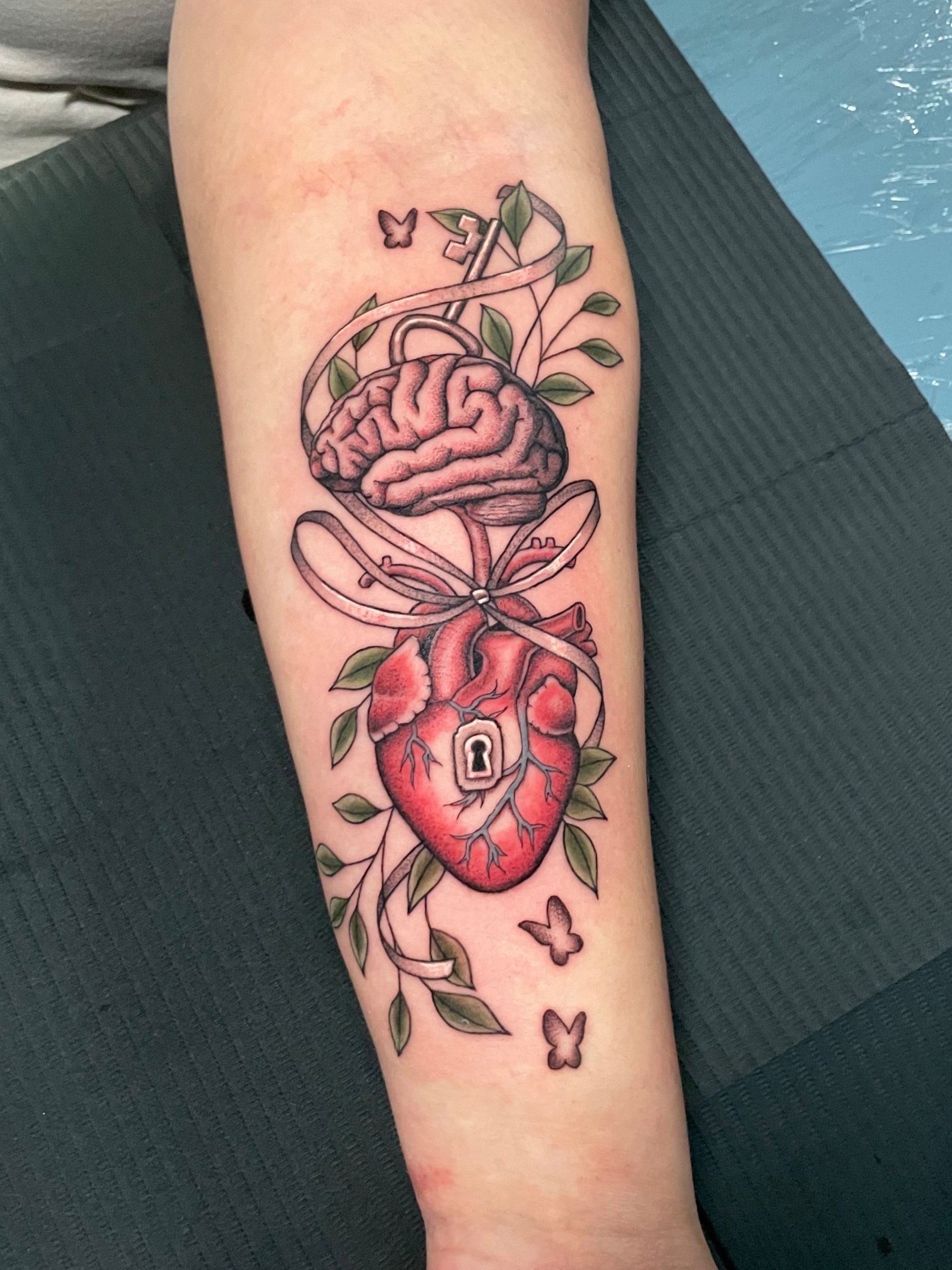 heart and brain and ribbon key and key hole tattoo with little butterflies.