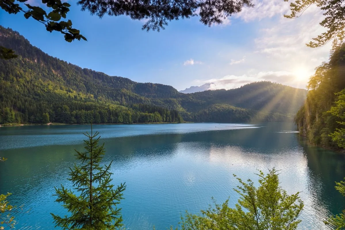 Blue mountain lake, sun on the horizon. Energy healing and integrative coaching combine chakra balancing and aura clearing with tools like emotional intelligence & mindfulness to get to the root of held patterns that cause emotional absorption.