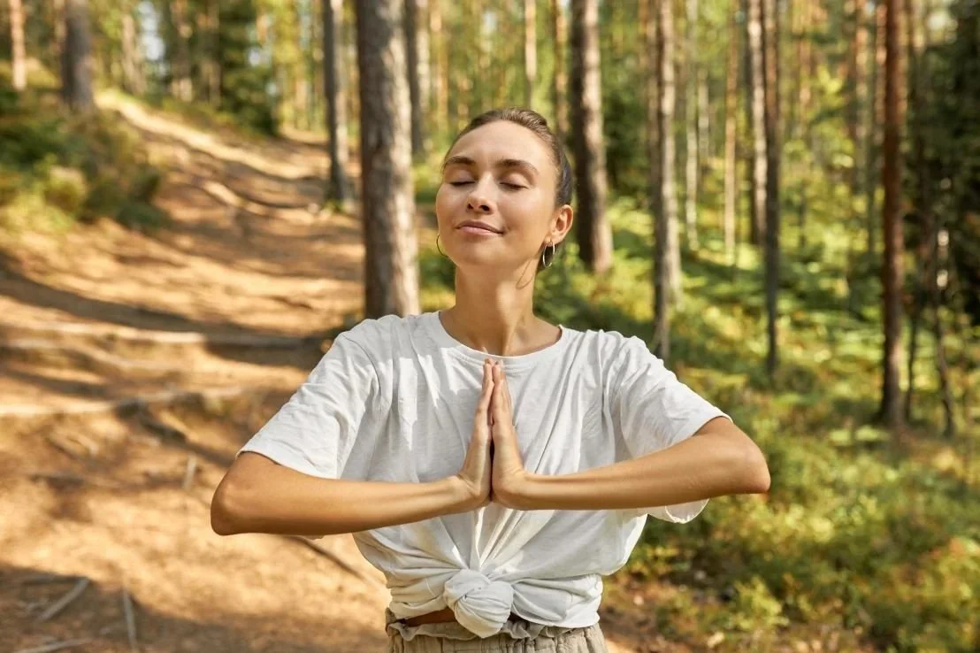 Brown haired women on a mountain path with praying hands. Energy Healing and Integration Sessions in Bozeman combines the powerful techniques of somatic awareness, mindfulness, emotional intelligence, and energy work to heal the mind body connection.
