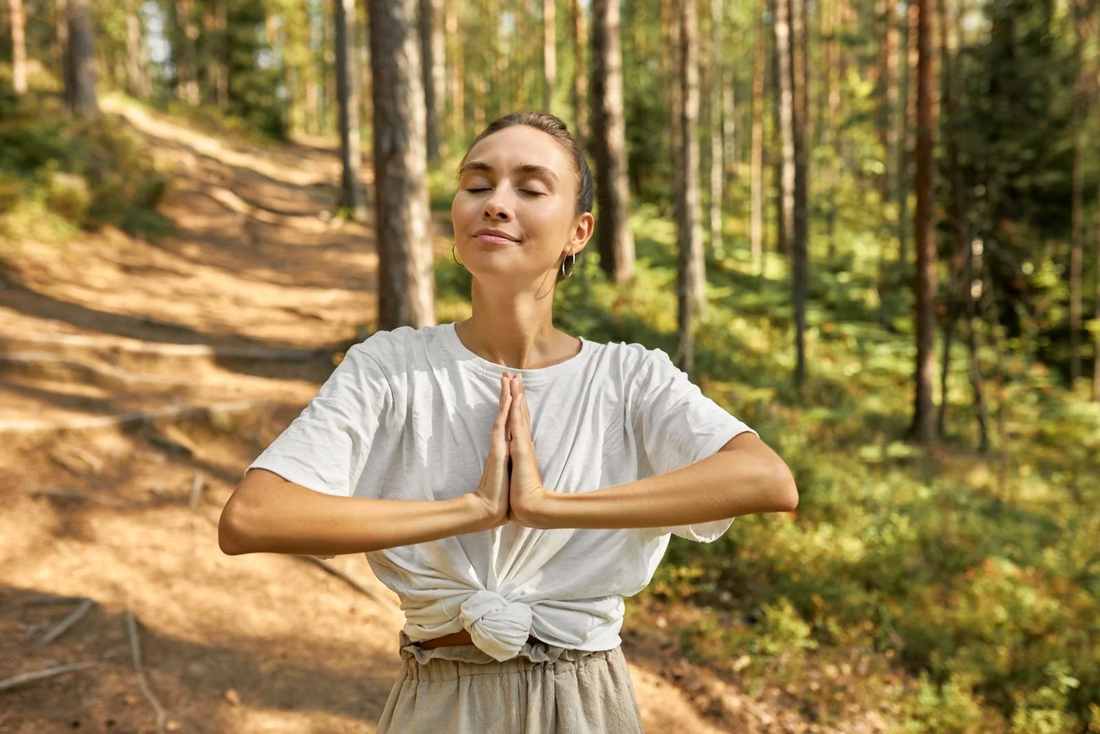 Brown haired women, grounding in the forest. Signs your energy may be out of balance happen from chakra imbalance , nervous system overload, and energy imbalance. Energy medicine can provide a support system to help you return to balance.