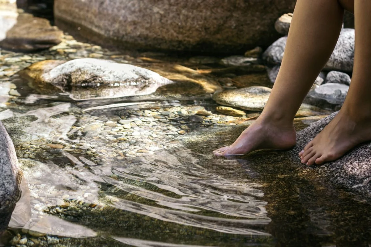 Rocky stream, feet in the water. This work helps you regulate your nervous system and release emotional blocks, to support your longevity and wellness.