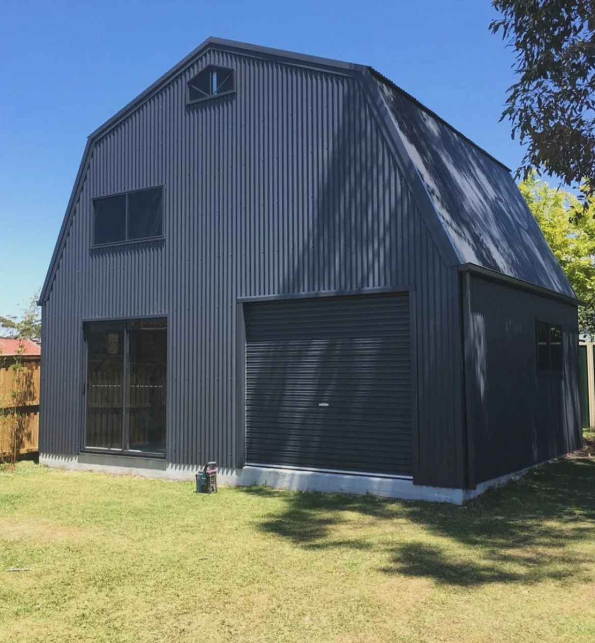 Black shed with sliding door and rollerdoor