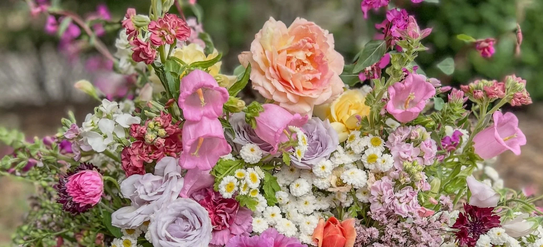 A colorful bouquet of various flowers including pink, purple, peach, and white blooms.