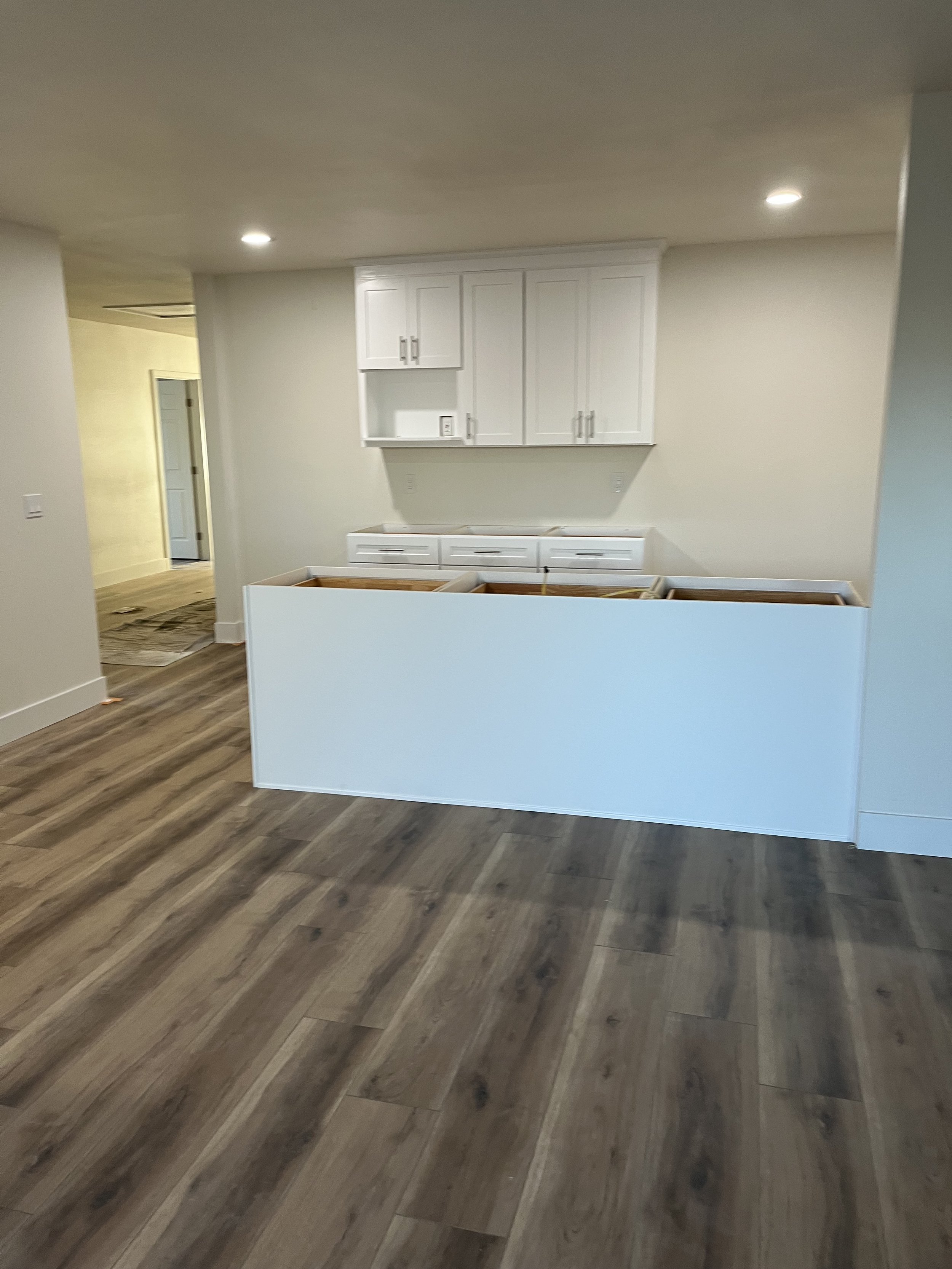 Interior view of a room under renovation with white cabinetry, a construction barrier, and wood flooring.