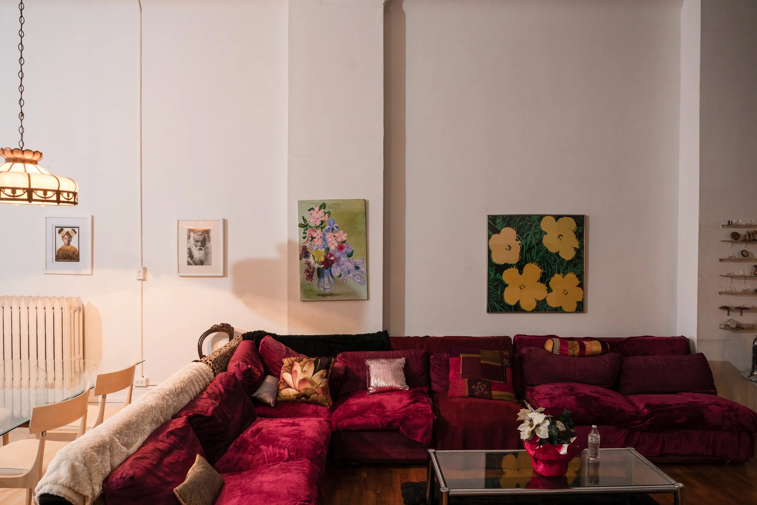 Large red sectional sofa beneath artwork in a historic loft apartment.