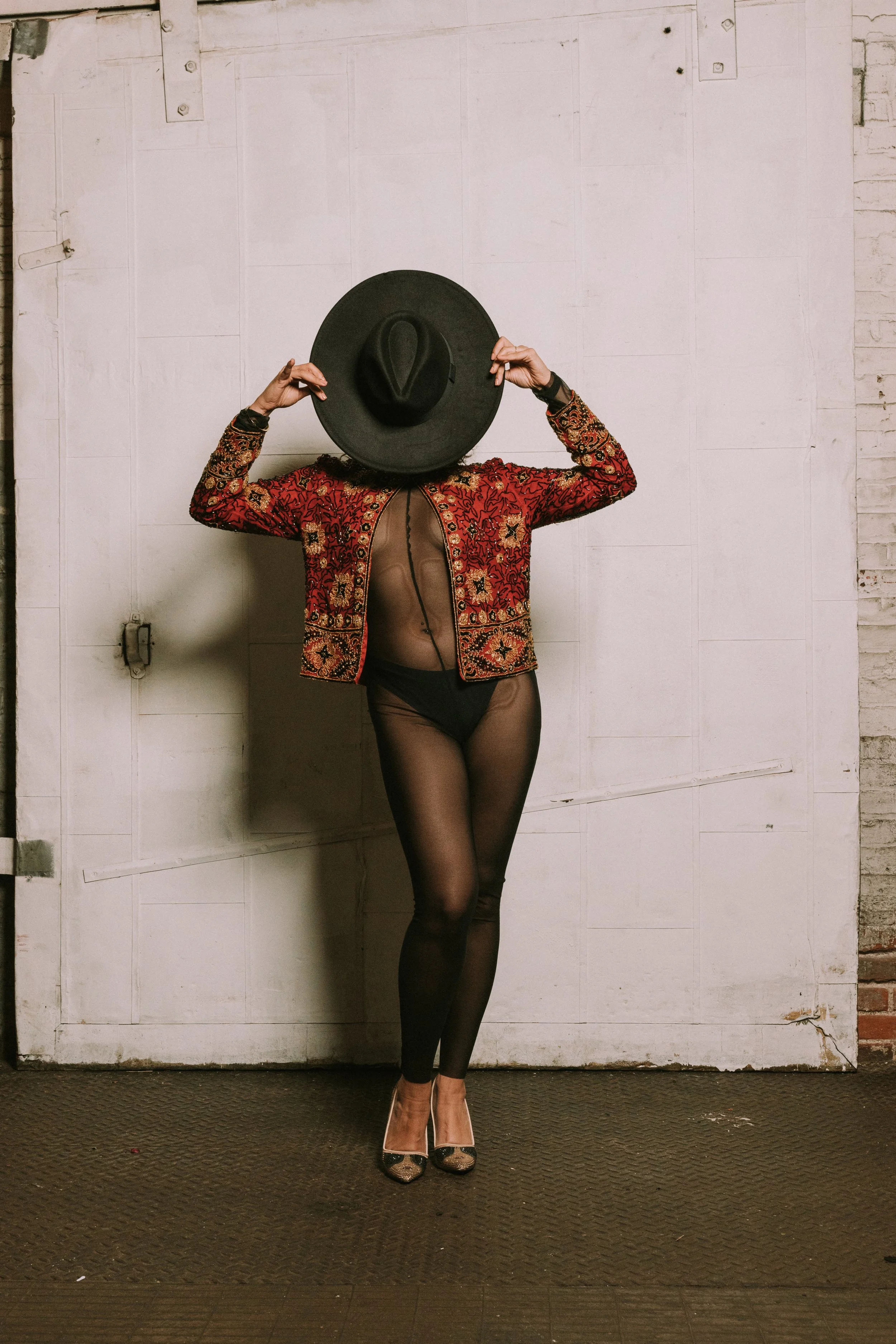 Full body portrait with red embroidered jacket and hat, studio-style editorial photography