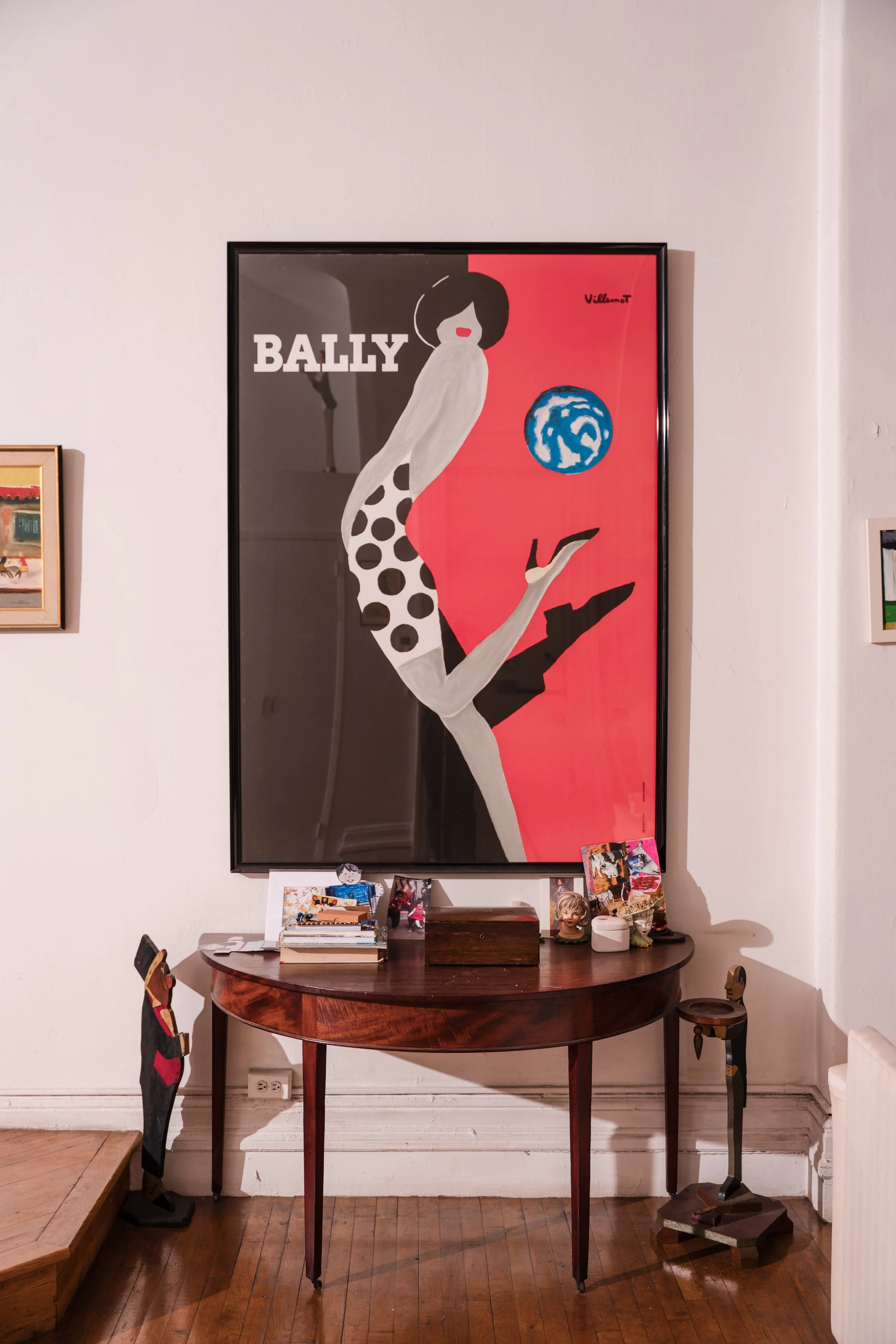 Bally fashion poster displayed above a mahogany table with family photographs.