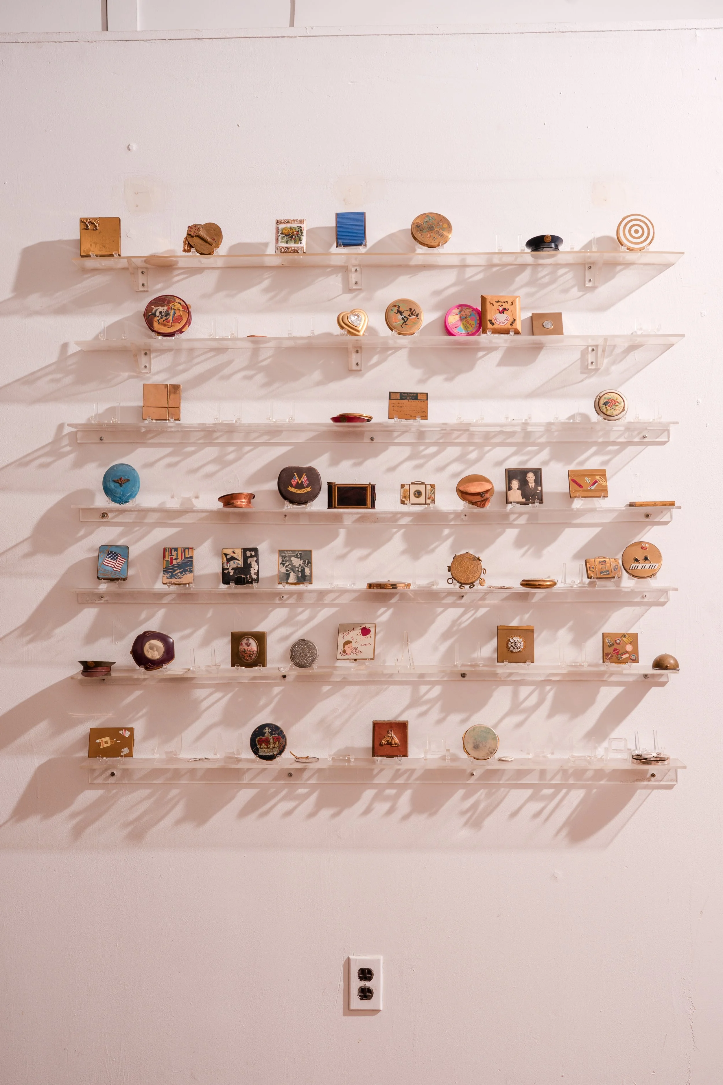 Close-up of vintage compact collection with empty spaces left where pieces were sold.