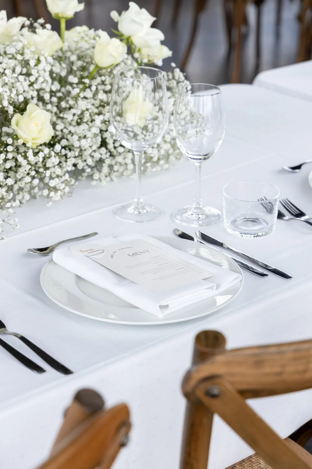 Detaljfoto av bordplassering til bryllup, med tallerken, bestikk, glass og meny
